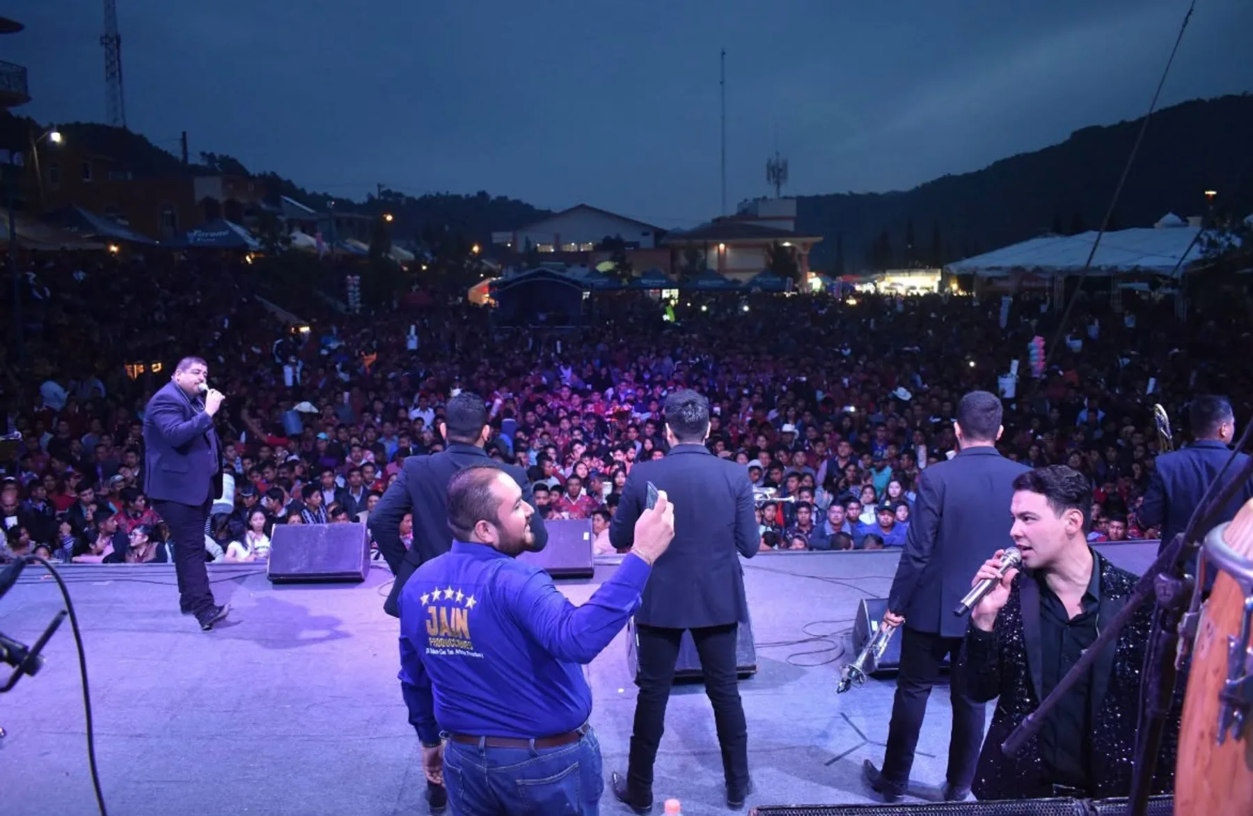 Escenario visto desde atrás con público masivo en evento producido por Jain Producciones
